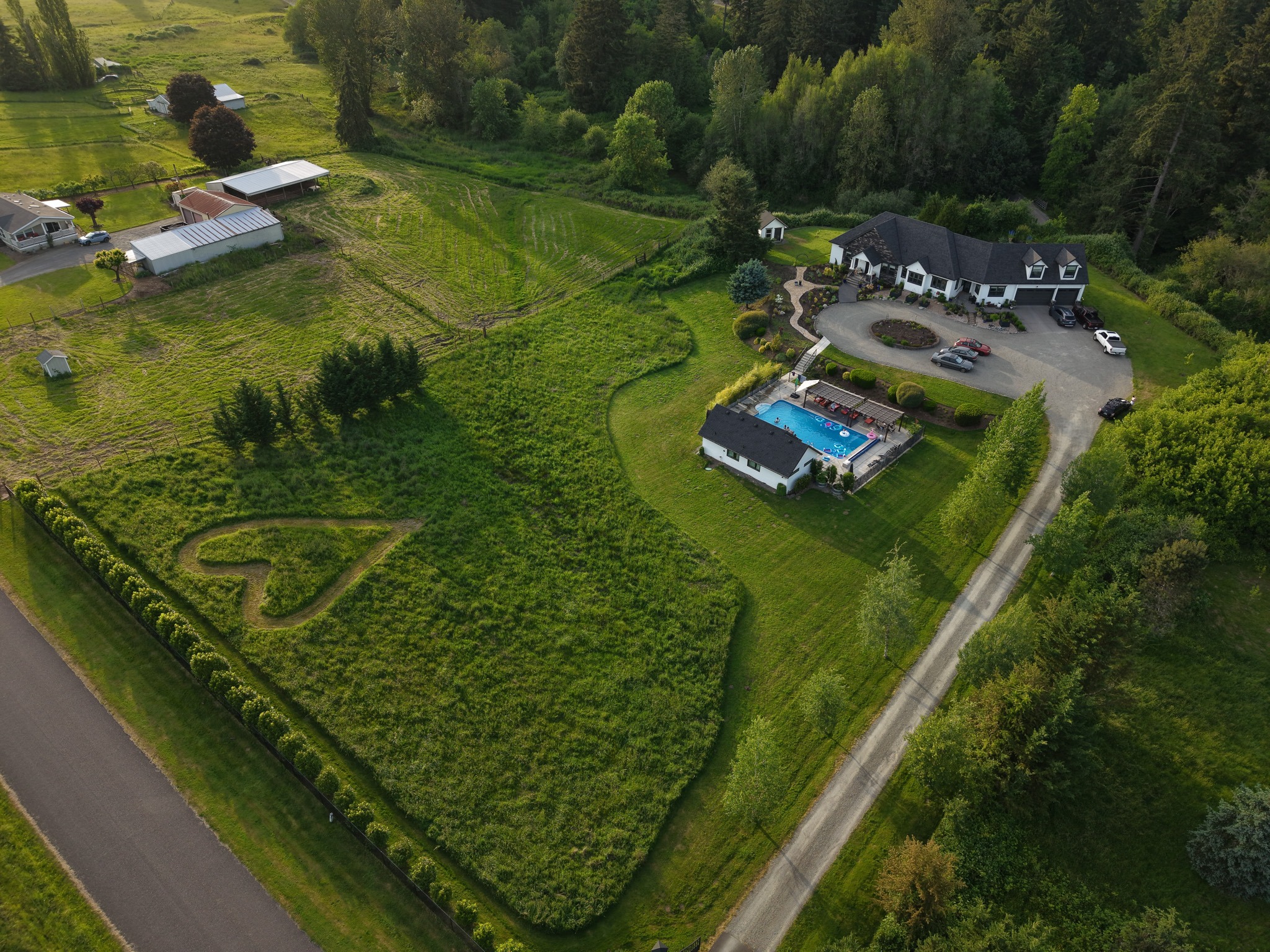 Aerial view of a large rural estate with a pool and surrounding property